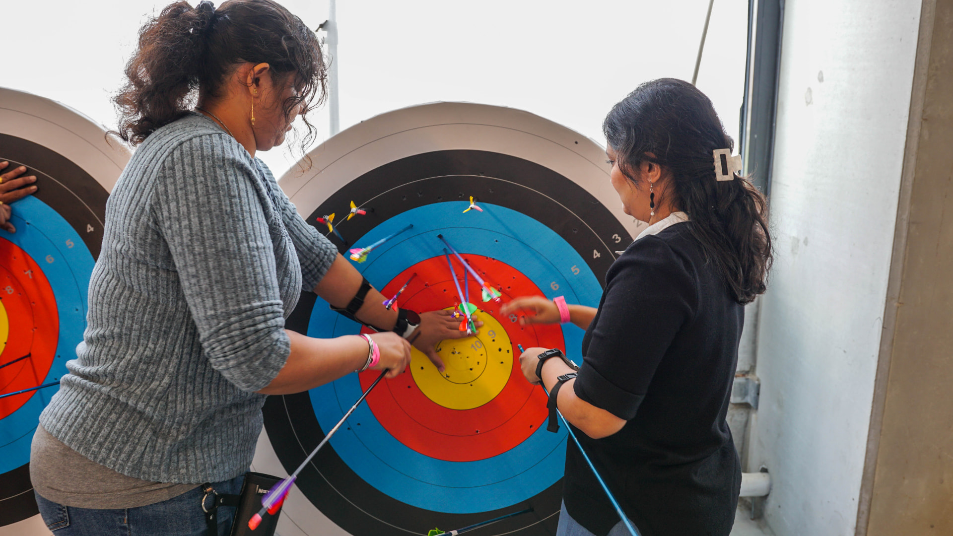 Two adults collecting arrows together at the target