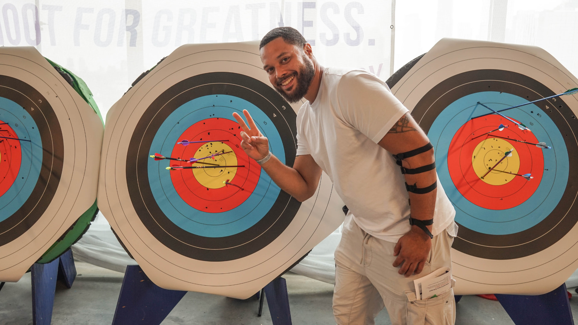 A smiling participant posing in front of three archery targets filled with arrows
